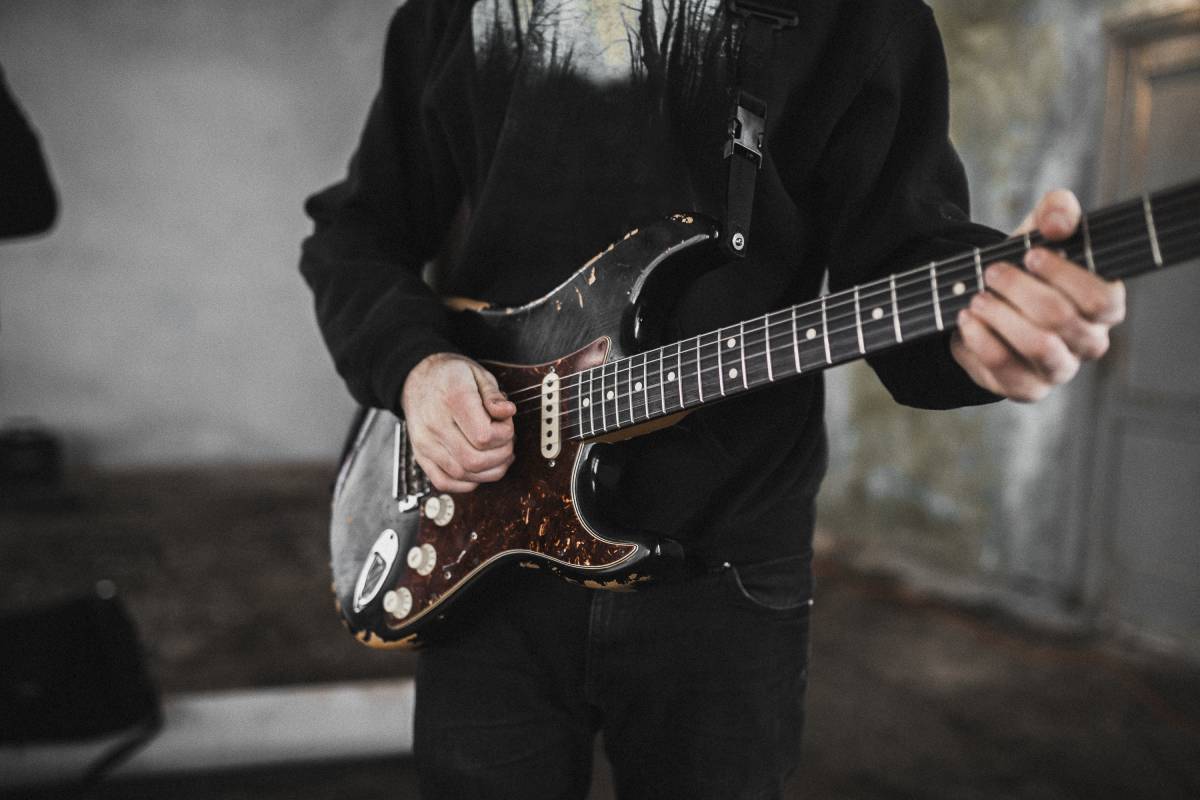 A man in a black hoodie playing an electric guitar.