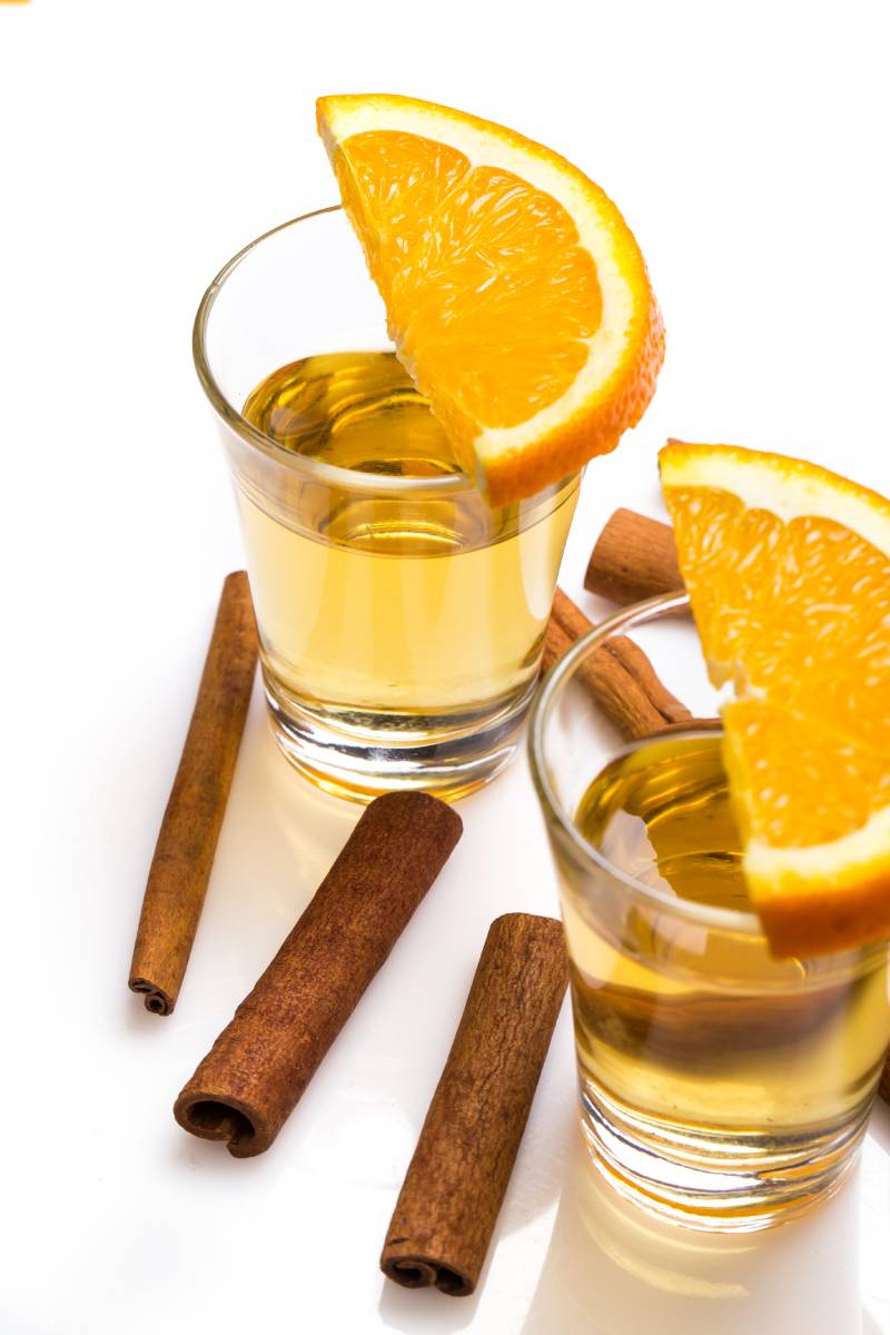 Two glasses with orange slices and cinnamon sticks.